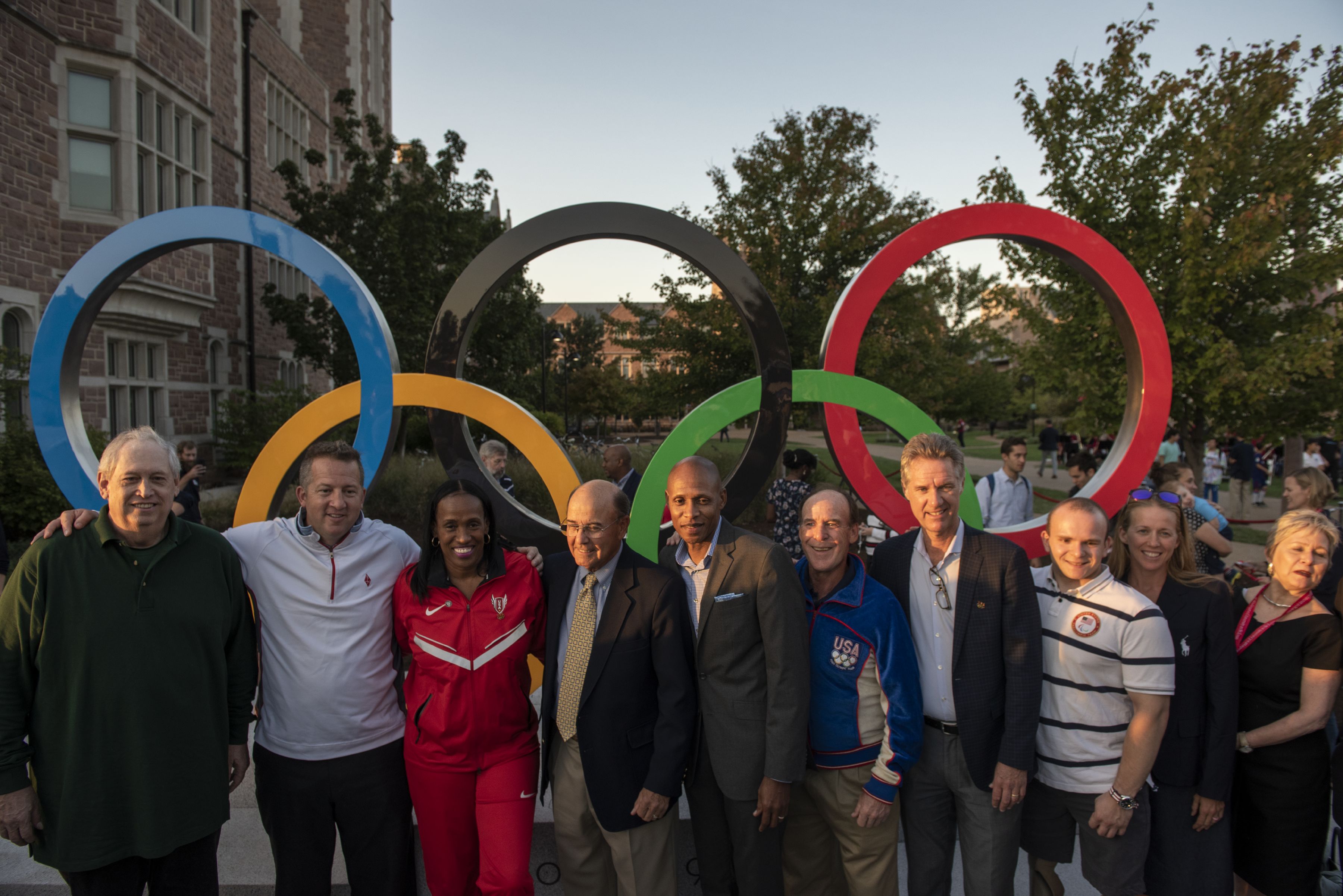 A group of people standing in front of the Olympic Rings sculpture